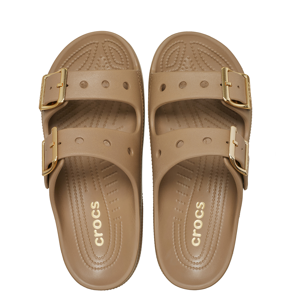 A pair of tan Crocs double-strap slide sandals with gold-tone buckle details, shown from a top-down view on a white background.
