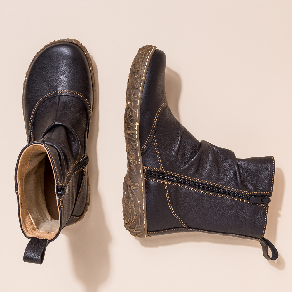 Pair of black leather boots on a beige background