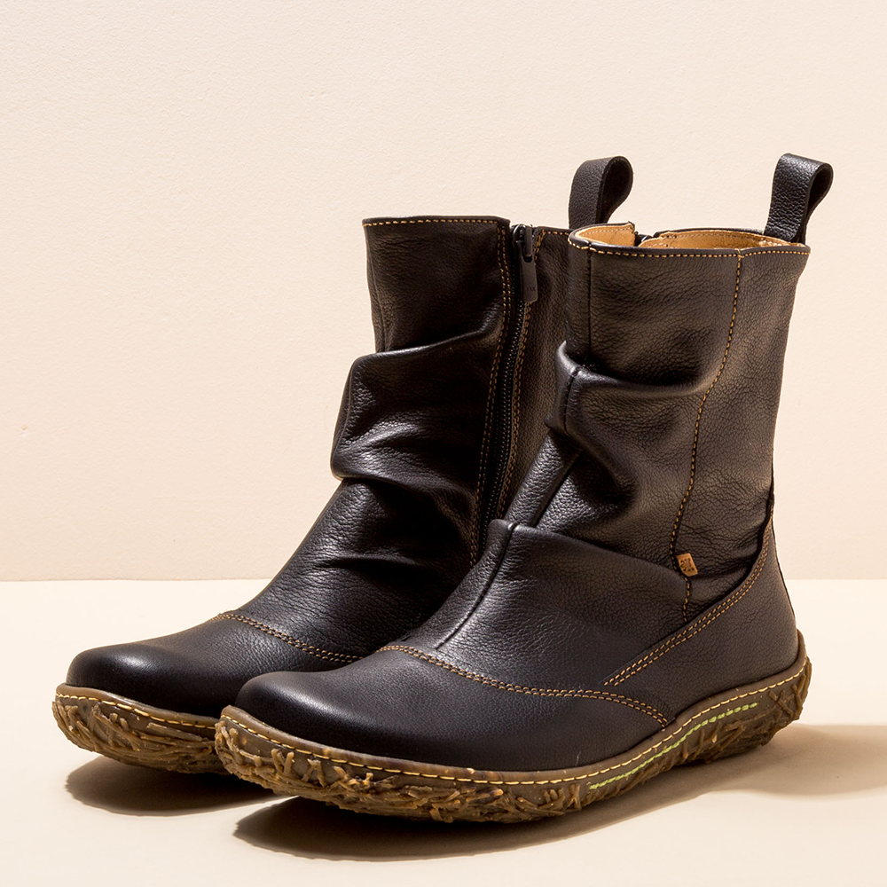 Pair of black leather boots on a beige background